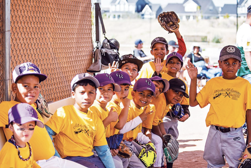 Team of young baseball players in yellow jerseys gathered in the dugout